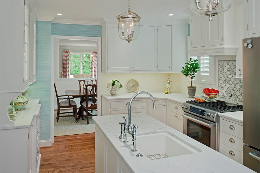 Transitional kitchen with white cabinetry, marble countertops, medium hardwood flooring, and light blue textured wallpaper
