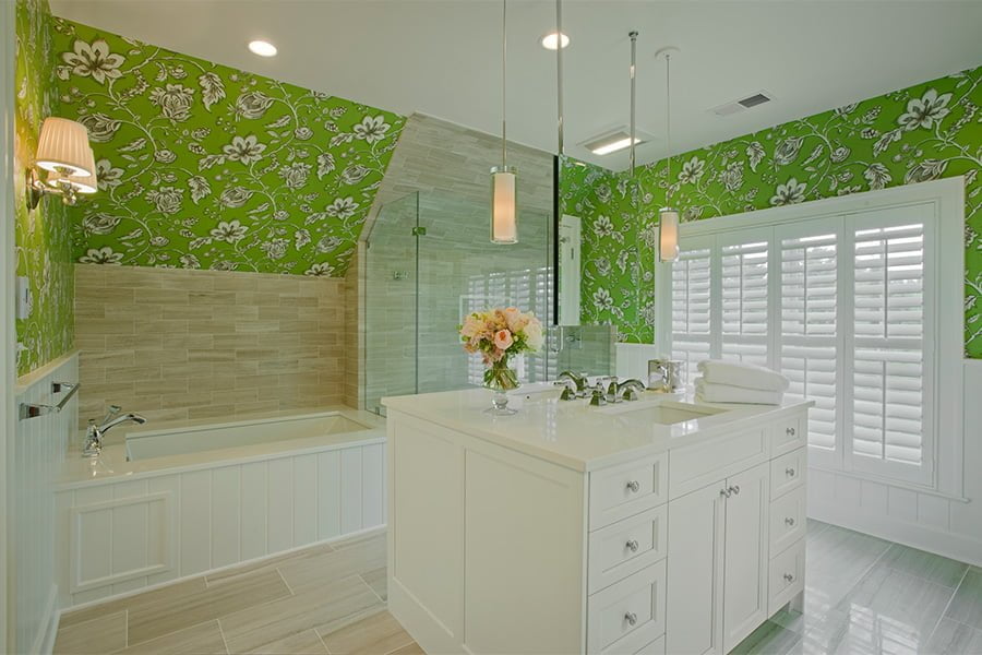 High end bathroom with custom white cabinetry, marble countertops, beige tile flooring and matching smaller tile backsplash, and vibrant green floral wallpaper
