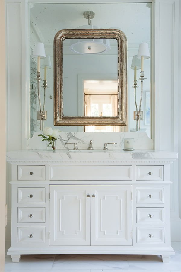 High end bathroom sink with white cabinetry, marble countertops, and ceiling-high mirror