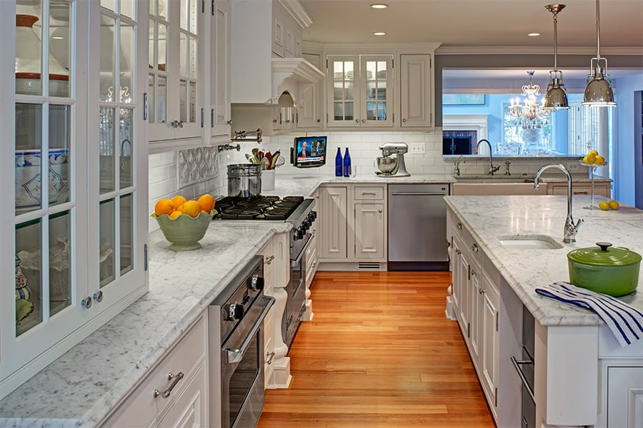High end kitchen with marble countertops and white cabinetry on medium hardwood flooring (island view) (different angle)