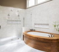 Modern bathroom with custom wooden bathtub, all glass shower, and light grey tile flooring and wall tile (different angle)