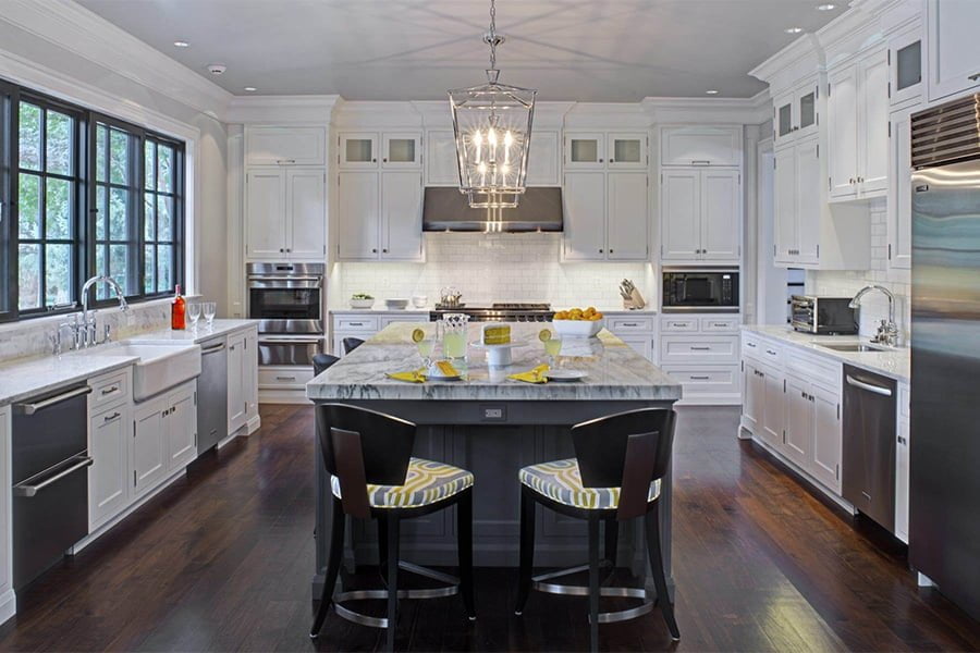 Open concept kitchen with white cabinetry, a gray center island and gray and white marble countertops