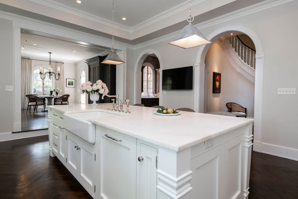 Custom white cabinetry with dark chevron hardwood flooring and off-white wall color, grey leather hi-top chairs (Front side)