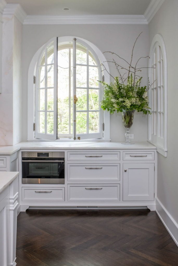 Custom white cabinetry with dark chevron hardwood flooring and off-white wall color