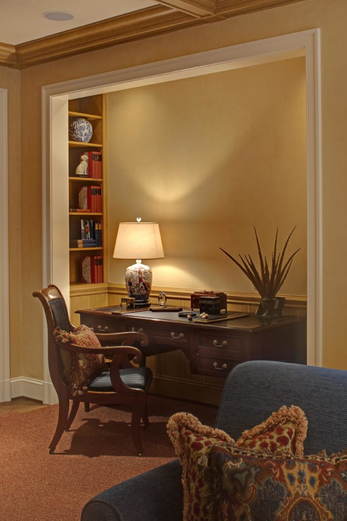 Traditional desk alcove with beige/yellow wall color, and antique wooden desk