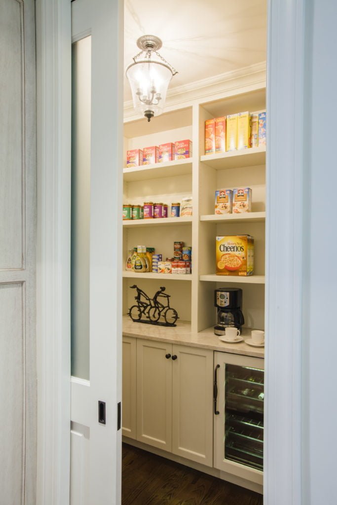 Transitional pantry with marble countertops, white cabinetry, and sliding door