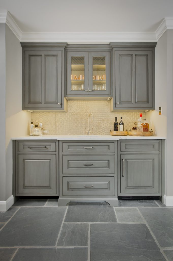 Transitional kitchenette with light grey custom cabinetry, grey stone tile flooring, marble countertop, and textured backsplash