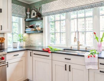 Transitional kitchen sink with custom white cabinetry and dark marble countertops, and a green-hue tile backsplash (Zoomed out)