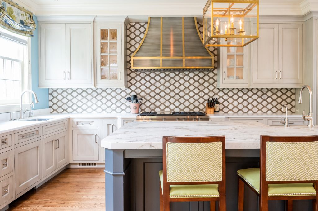 Transitional kitchen with marble countertops, decorative tile backsplash, and accented gold metal