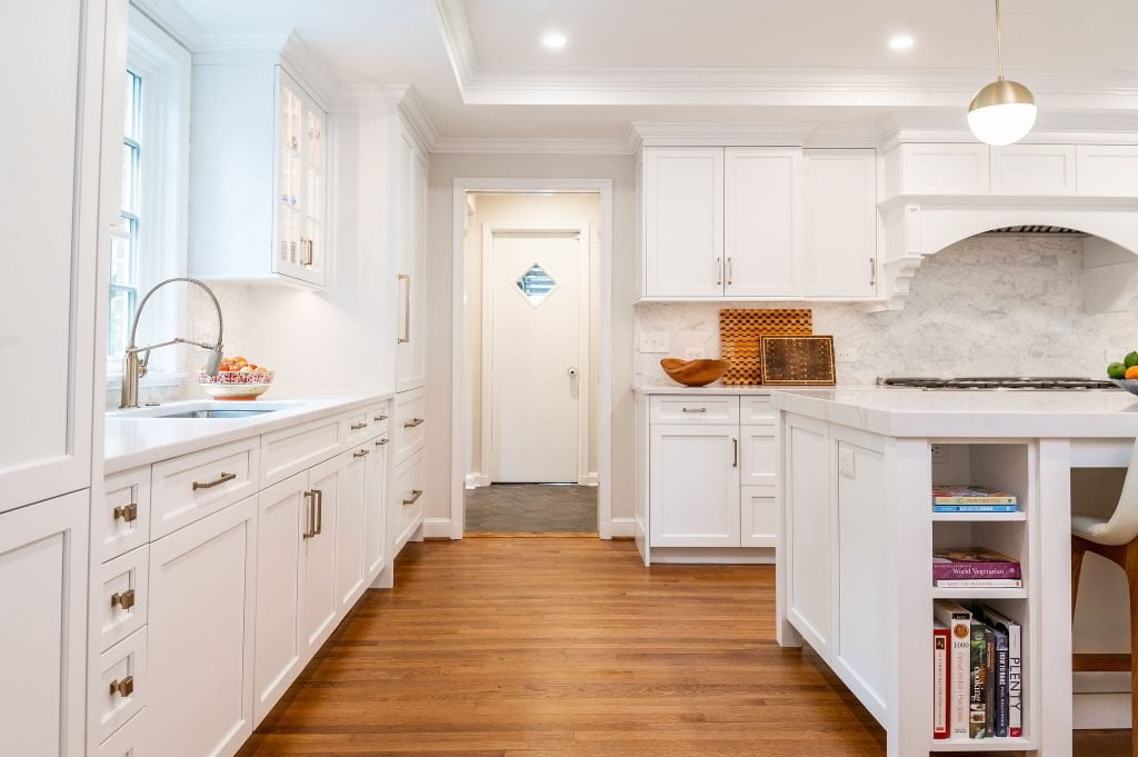 Transitional kitchen with white cabinetry, and marble countertop and backsplash (Through doorway)