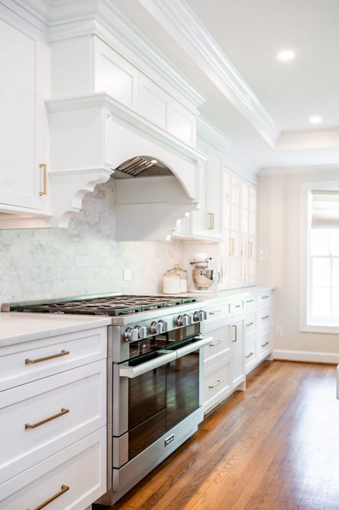 Transitional kitchen with stainless steel oven, white cabinetry and medium hardwood flooring