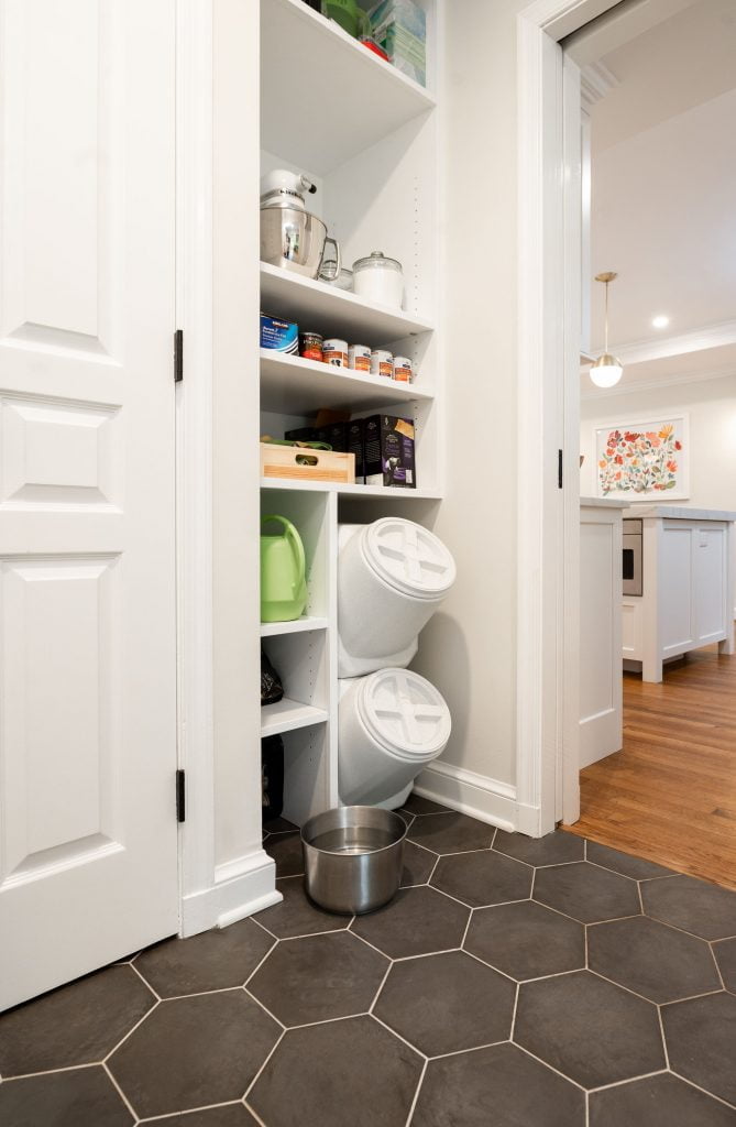 White cabinet pantry/pet feeding area with black hexagonal tile flooring