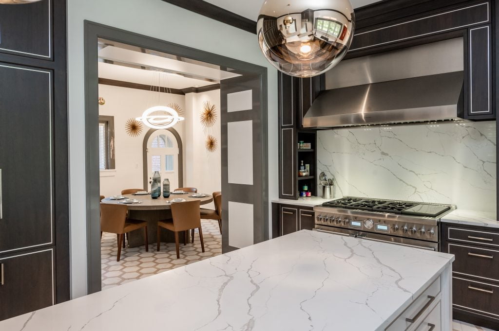 Modern/high end kitchen and island with all marble countertops, custom dark cabinetry and custom white cabinetry on island, and decorative hexagonal tile flooring (different view)