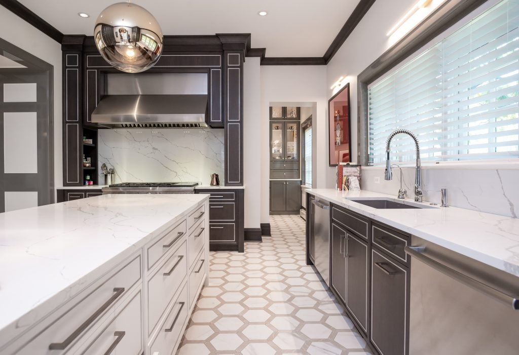 Modern/high end kitchen and island with all marble countertops, custom dark cabinetry and custom white cabinetry on island, and decorative hexagonal tile flooring