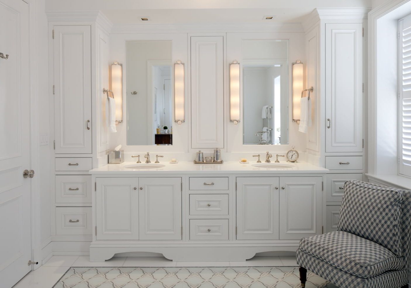 High end bathroom with all white cabinetry and marble countertops, with floor-to-ceiling storage