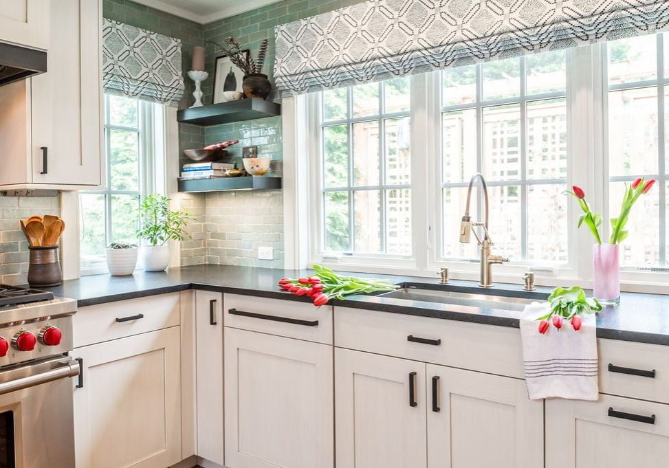 Transitional kitchen sink with custom white cabinetry and dark marble countertops, and a green-hue tile backsplash (Zoomed out)