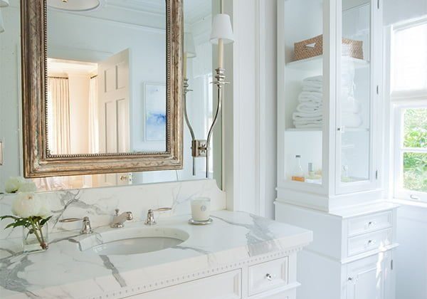 High end bathroom with custom white cabinetry and marble tile flooring and countertops