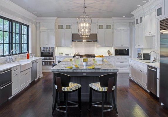 Open concept kitchen with white cabinetry, a gray center island and gray and white marble countertops.