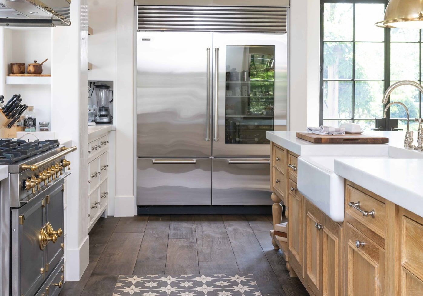 Transitional kitchen with light wood cabinetry and white marble countertops, stainless steel appliances, and dark hardwood flooring