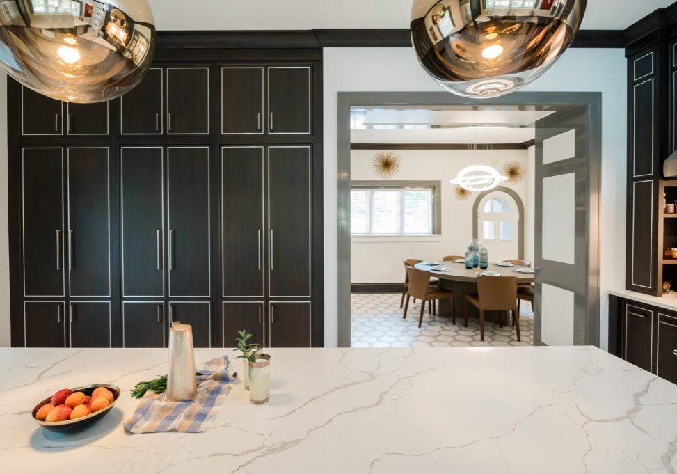 Custom floor-to-ceiling dark cabinetry from behind marble island countertop