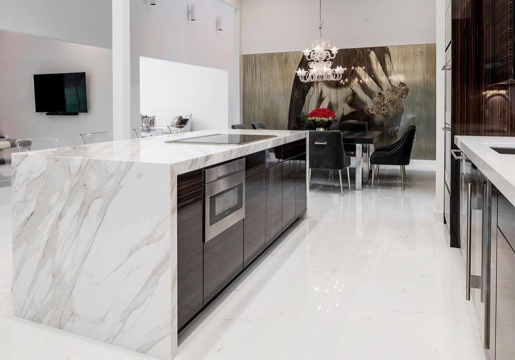 Modern style kitchen with dark hardwood cabinetry, white marble countertops and flooring, stainless steel appliances