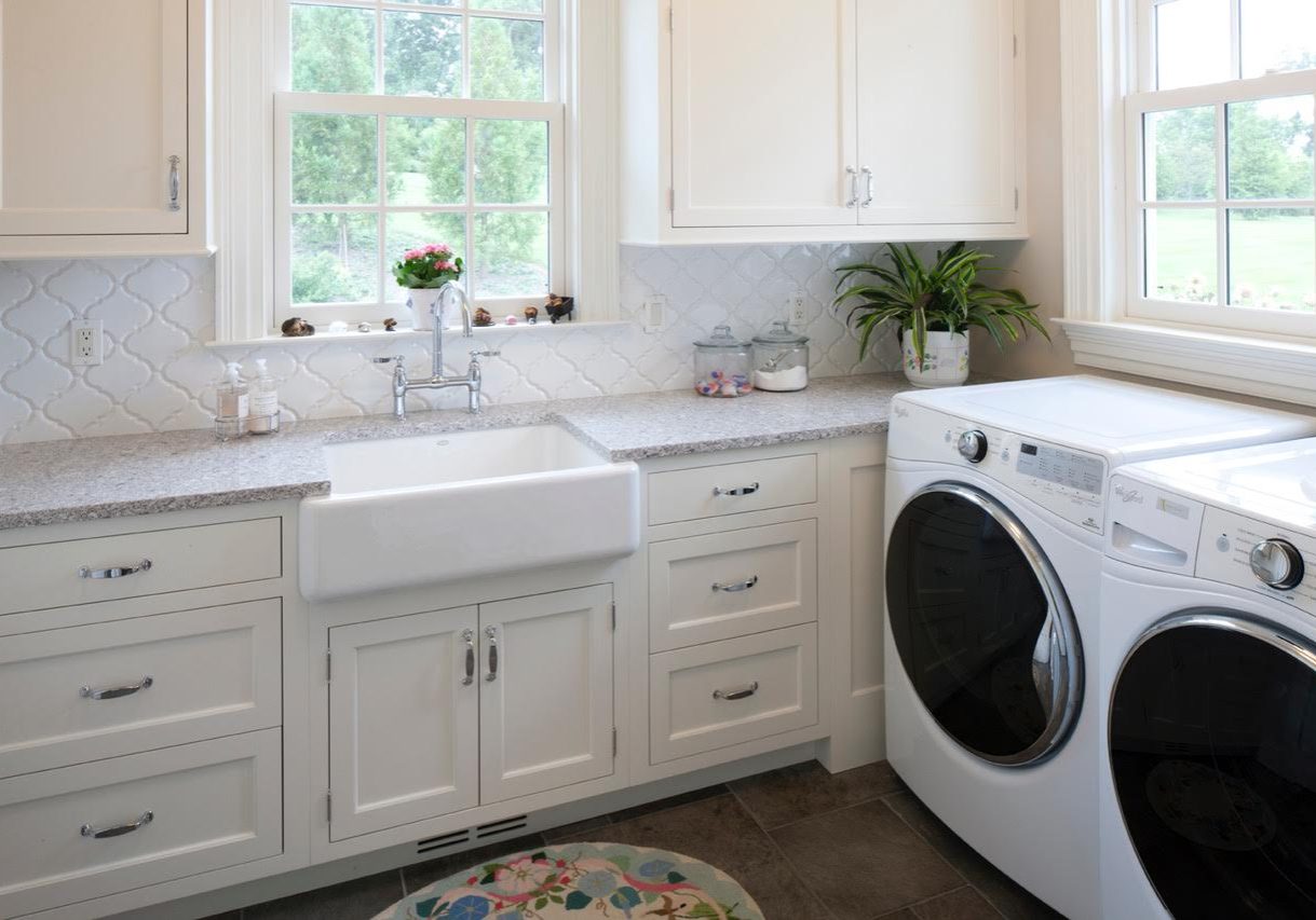 Transitional laundry room with white cabinetry, dark tile flooring, granite countertops, and white decorative tile backsplash